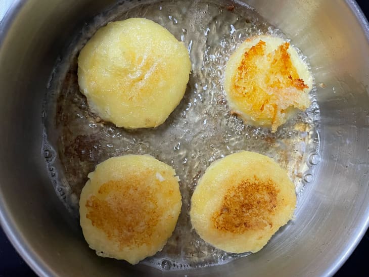 Honey glazed cheesy potato pancakes cooking in pot.