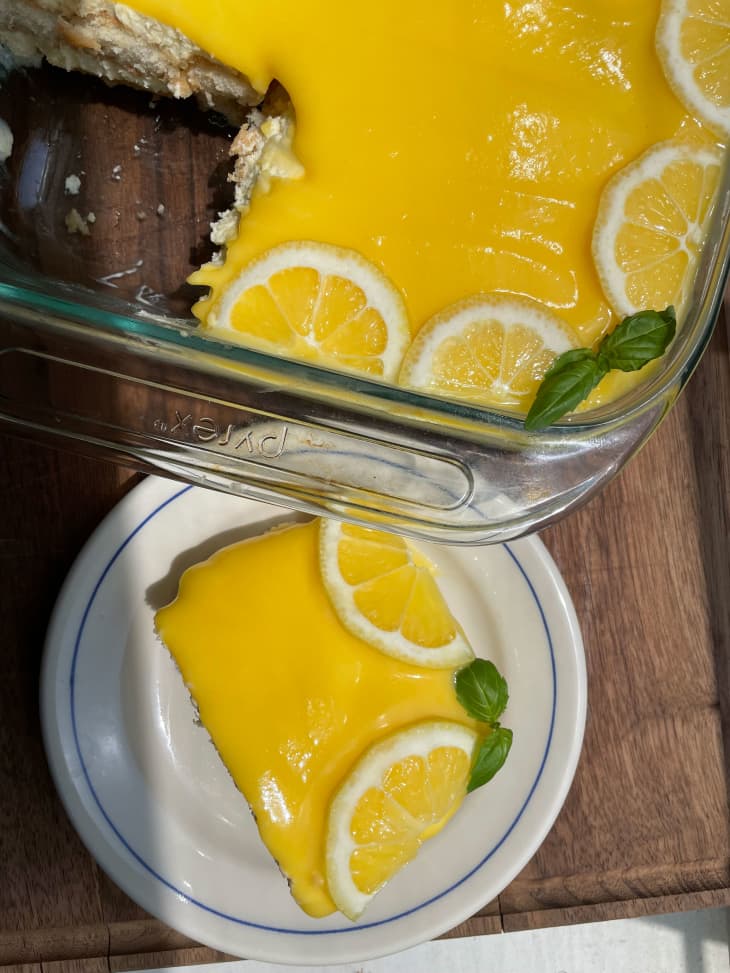 Slice on lemon tiramisu on a plate with the remaining portion in baking dish.