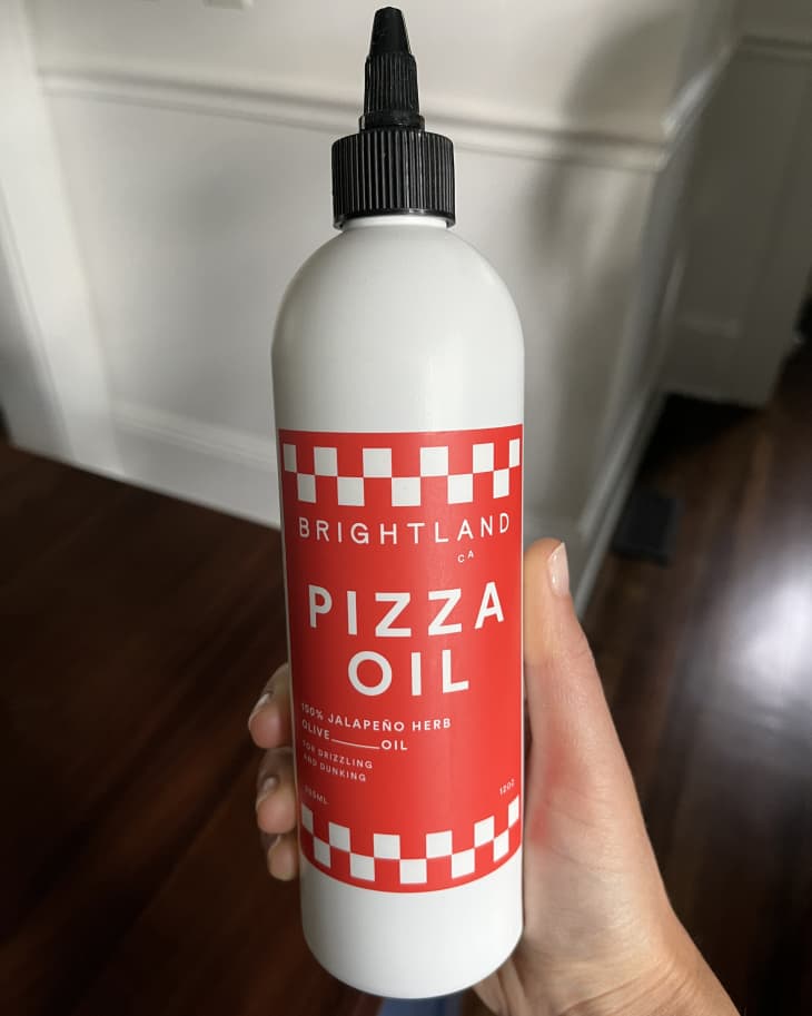 someone holding up bottle of brightland pizza oil