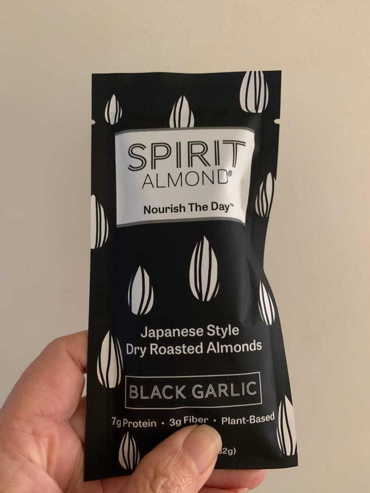 Someone holding packet of Black Garlic Spirit almonds.