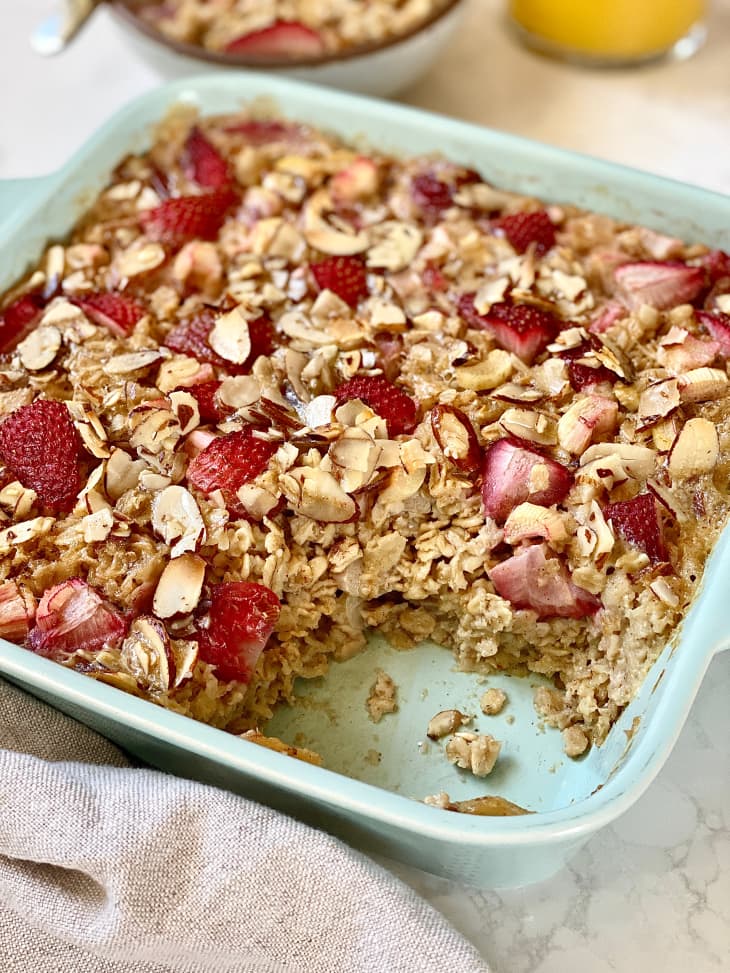 Portion scooped out of strawberry rhubarb baked oatmeal in baking dish.