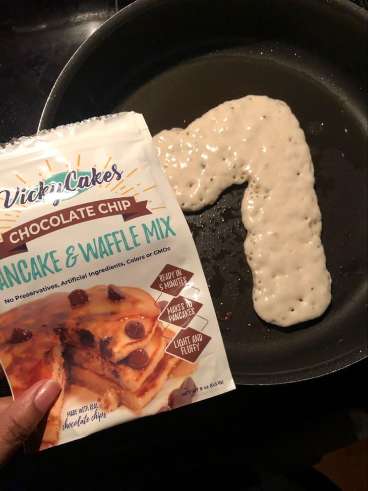 Someone pouring Vicky's pancake mix into skillet.