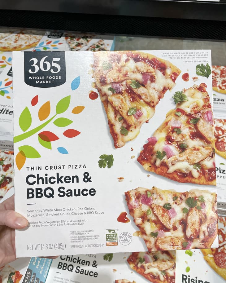 Someone holding up frozen Whole Foods 365 Thin Crust Chicken &amp; BBQ Sauce Pizza in store
