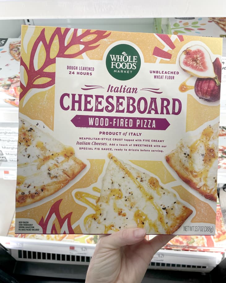 Someone holding up frozen Whole Foods 365 Italian Cheeseboard Wood-Fired Pizza in store