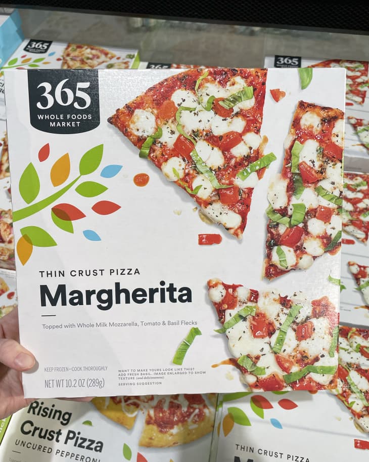 Someone holding up frozen Whole Foods 365 thin Crust Margherita Pizza in store