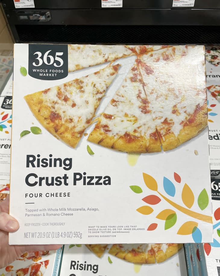 Someone holding up frozen Whole Foods 365 Rising Crust Four Cheese Pizza  in store