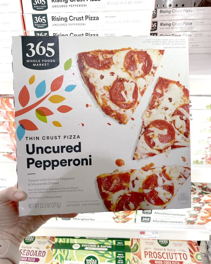 Someone holding up frozen Whole Foods 365 Thin Crust Uncured Pepperoni Pizza in store