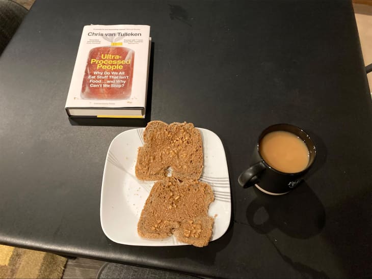 Peanut butter toast with cup of tea on table with a book about processed food above.
