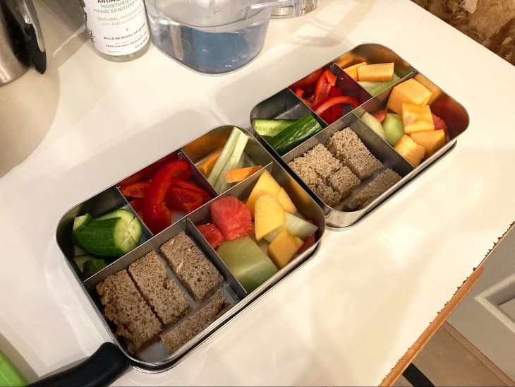Healthy lunch of whole grain bread, peppers, cucumber and diced fruit in bento box.