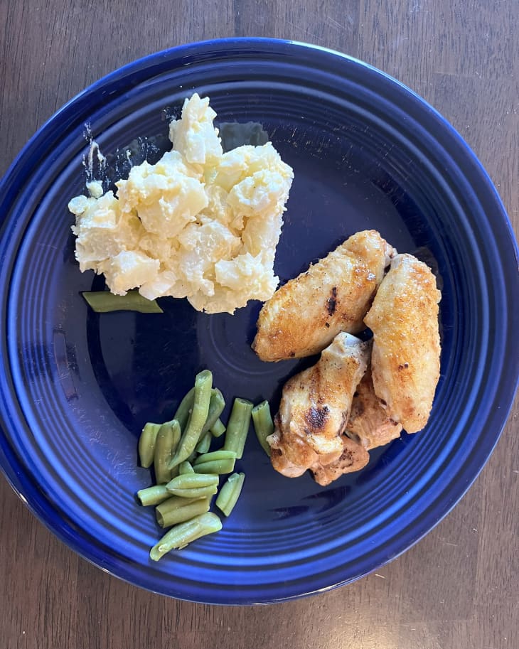 Chicken wings, green beans, potato salad on blue plate