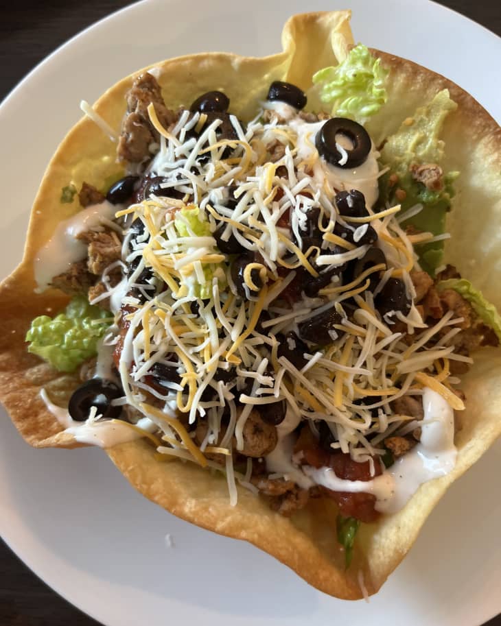 Taco salad in flour tortilla shell on white plate
