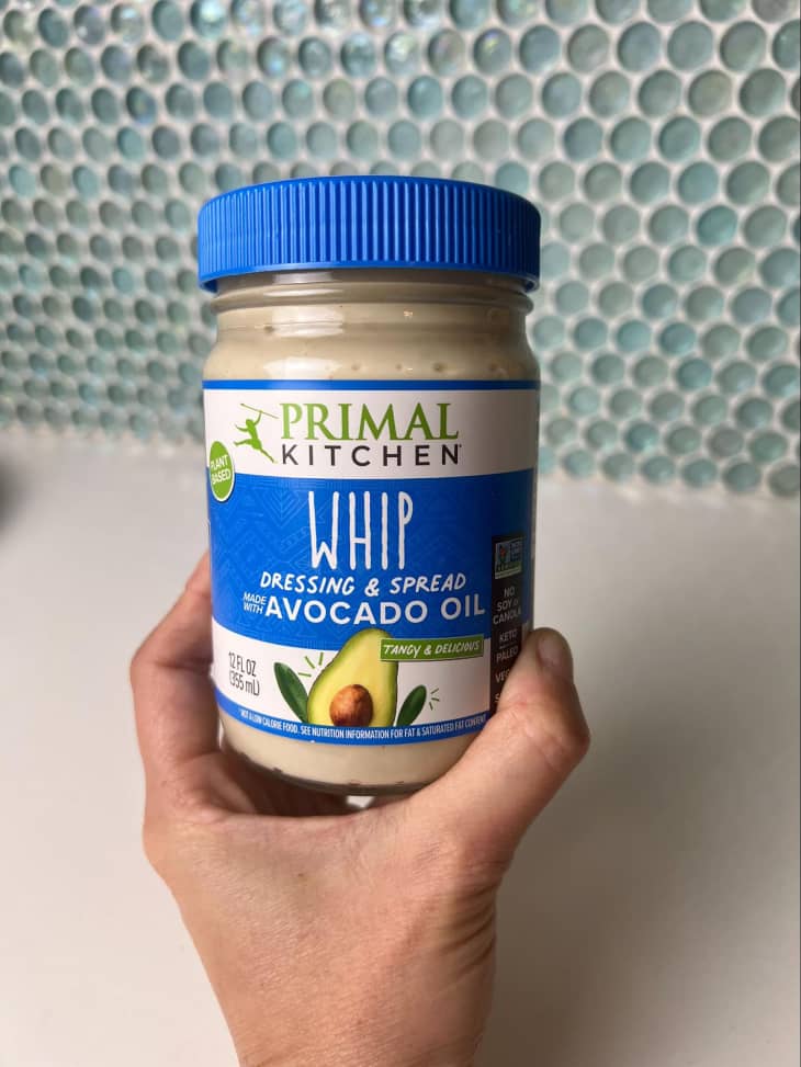 Someone holding jar of Primal Kitchen's Whip dressing and spread.