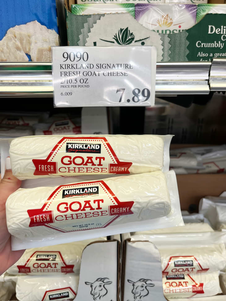Someone holding up packages of goat cheese in costco.