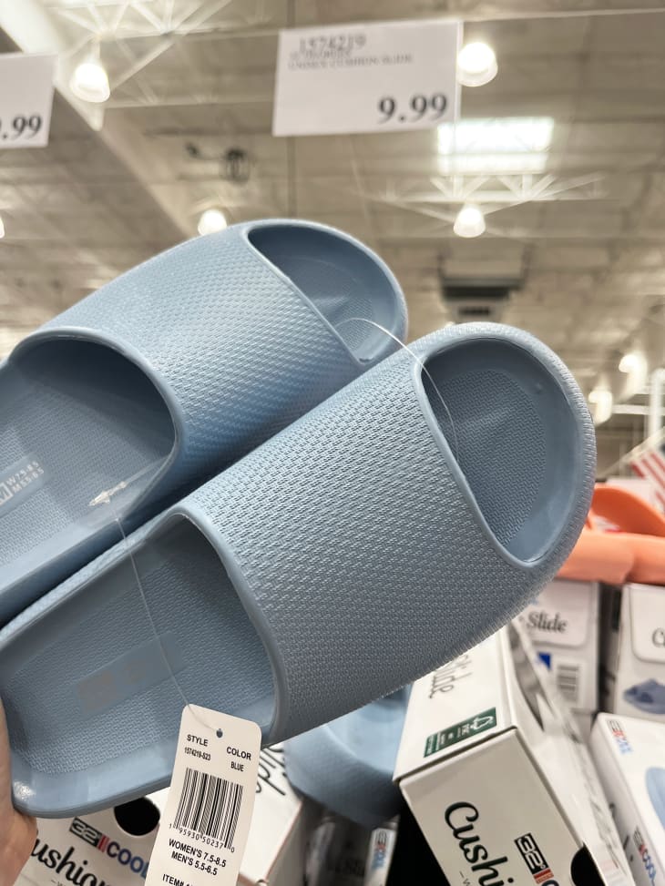 Someone holding up blue sandals in Costco.