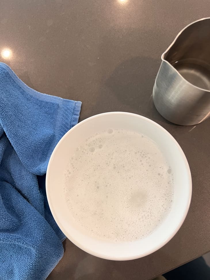 Overhead photo of a dishwasher tablet dissolving in a white bowl