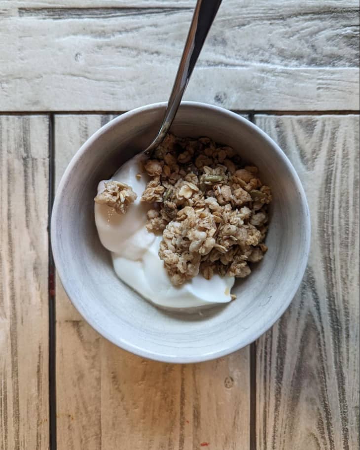 wood background, small bowl, yogurt, granola, white bowl, silver spoon