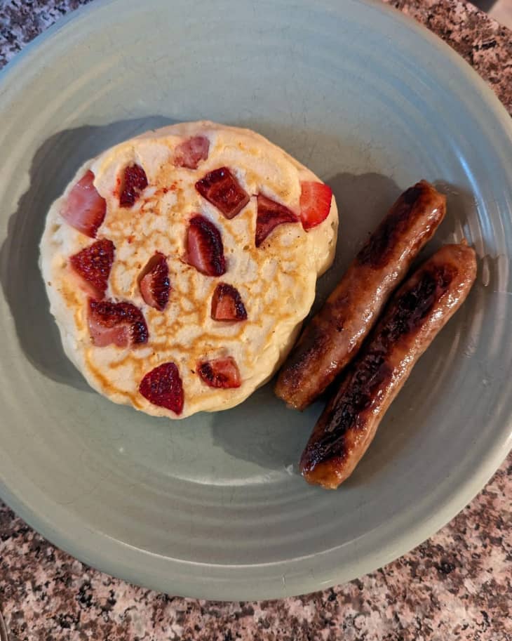 strawberry pancake, 2 sausage links, green plate, brown marbled counter