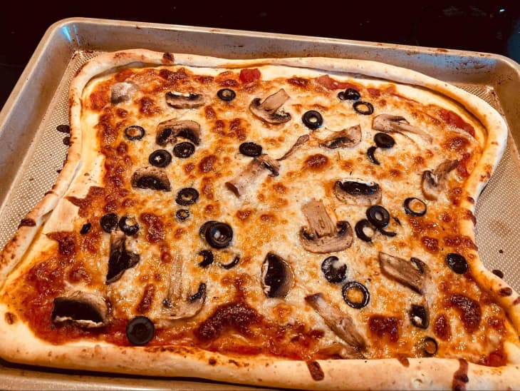 Homemade pizza on baking sheet.