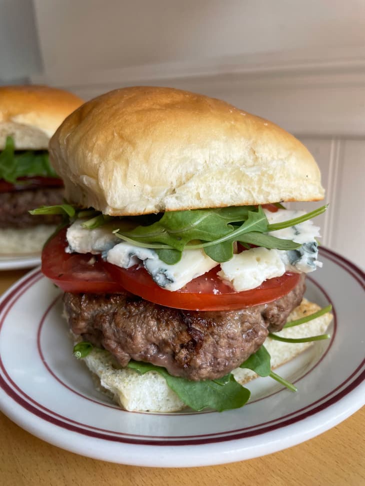 Plated burger assembled with blue cheese and tomatoes.