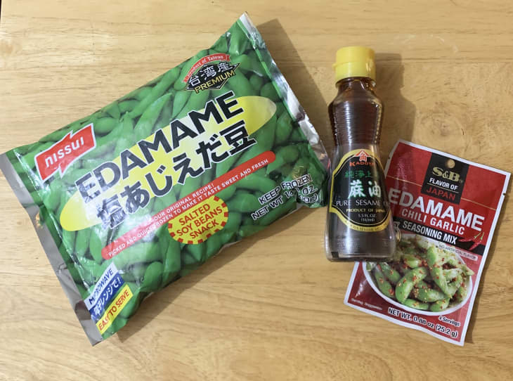 edamame package, sesame oil bottle, and edamame chili garlic seasoning packet on wood surface