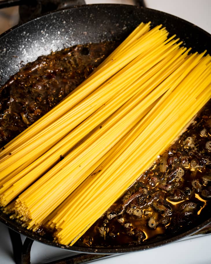 Dried noodles in skillet to make french onion soup noodles.