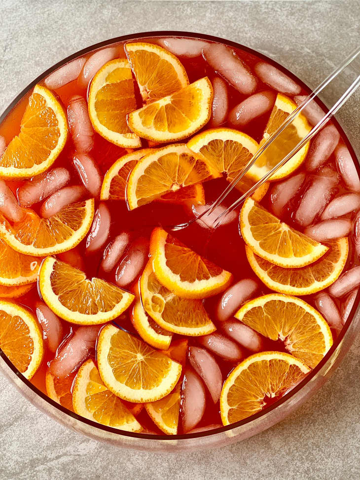Sparkling spritz punch topped with orange sliced in punch bowl with ladle on the side.
