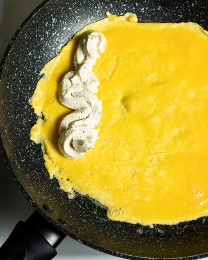 Whipped cheesed placed on top of eggs in skillet.