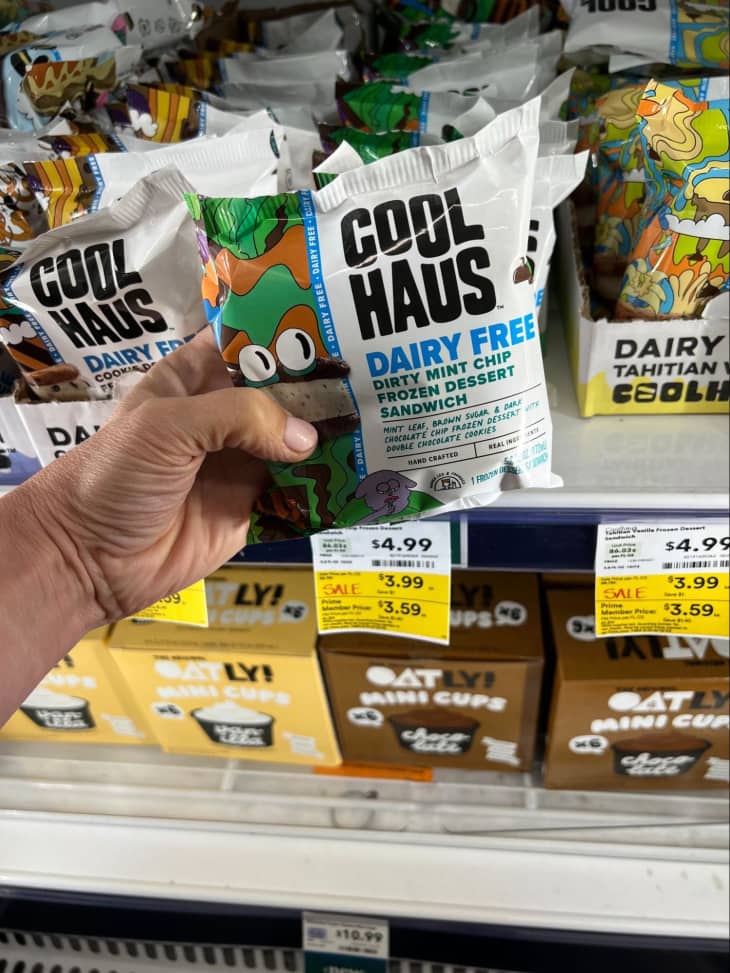Someone holding package of Cool Haus Dairy Free Dirty Mint Chip dessert sandwich.