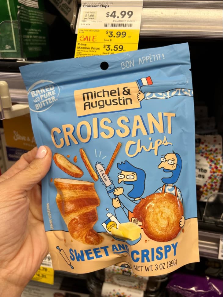 Someone holding Michel &amp; Augustin croissant chips in grocery store.