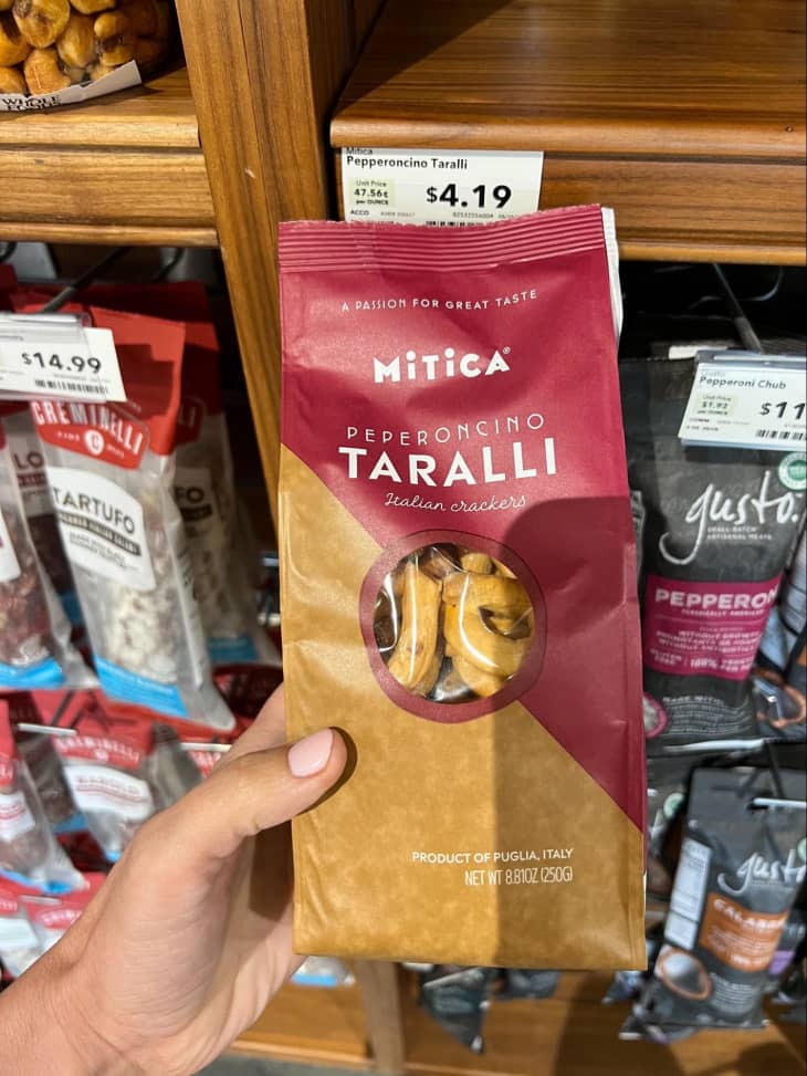 Someone holding Peperoncino Taralli Italian crackers in store aisle.