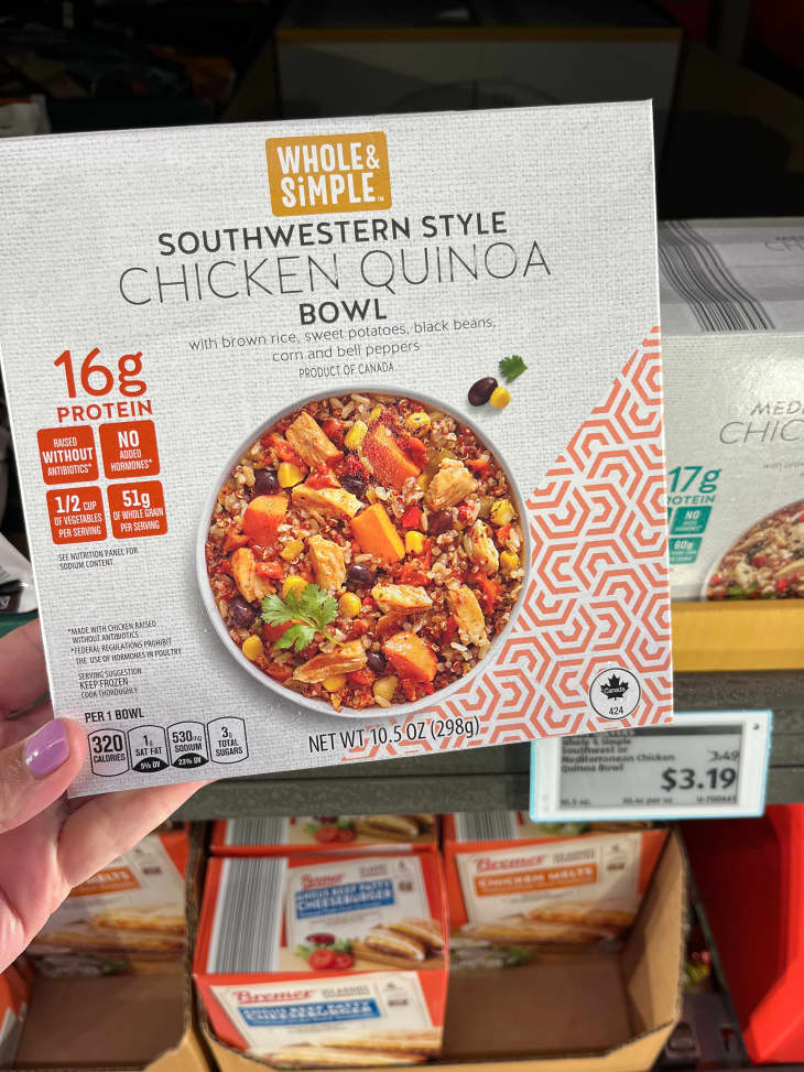 Someone holding box of chicken quinoa bowl.