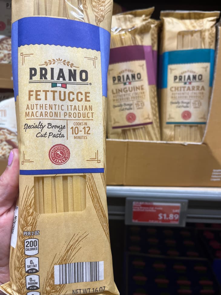 Someone holding package of dried fettucce pasta.
