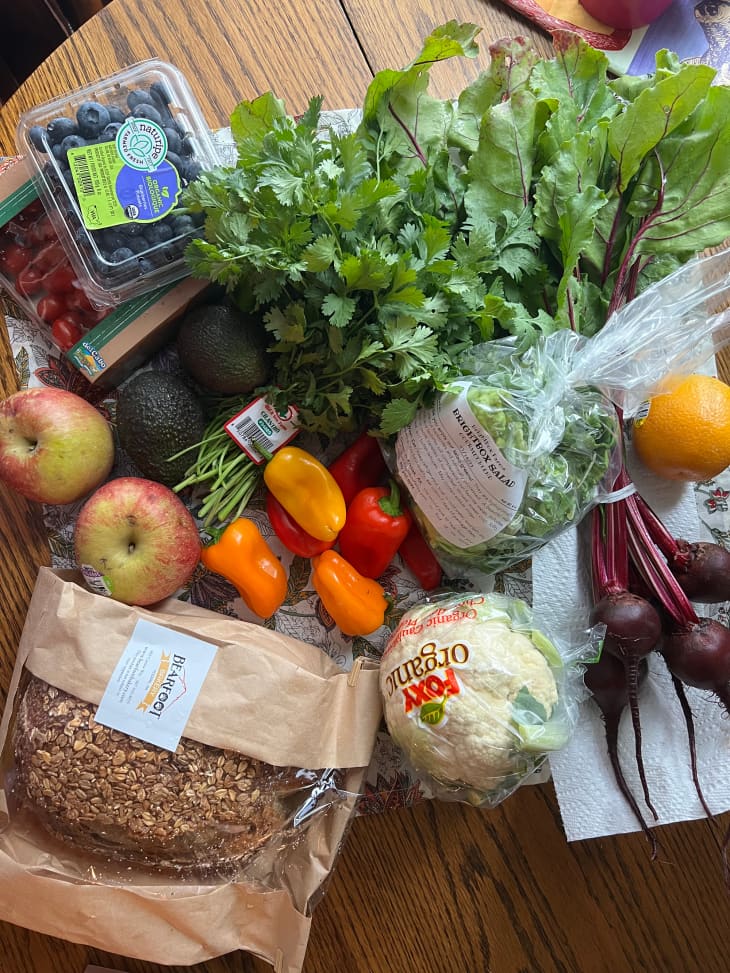 Grocery haul of produce and bread on dining table.