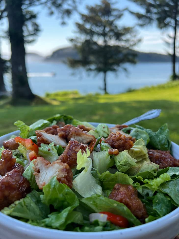 Someone sitting in a park eating a fried chicken salad.