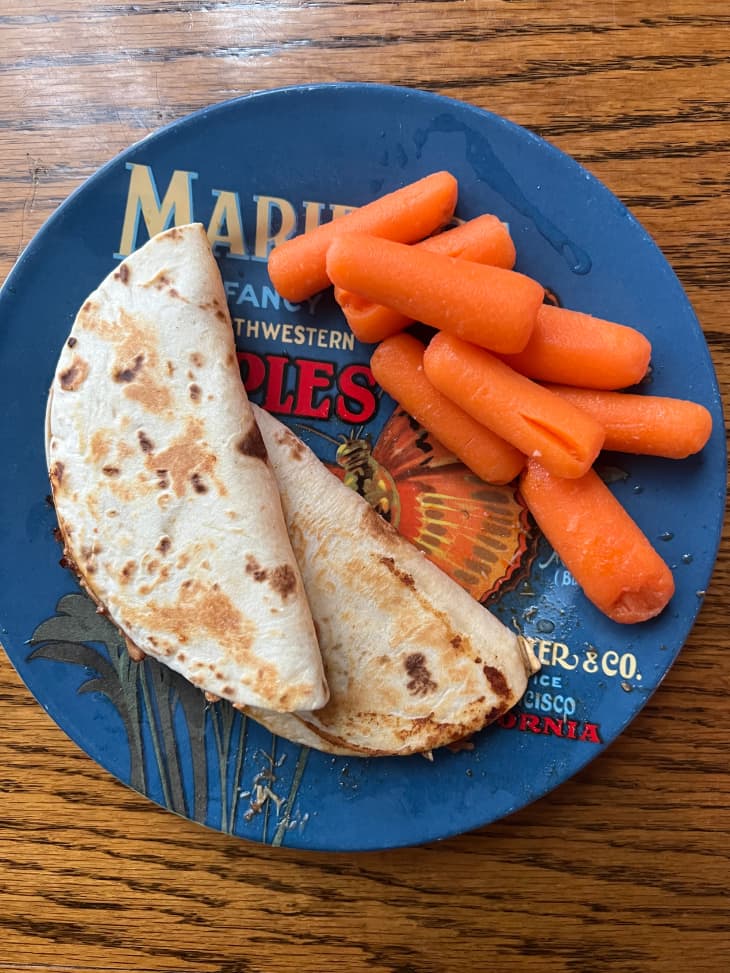 Two quesadillas on plate with baby carrots.