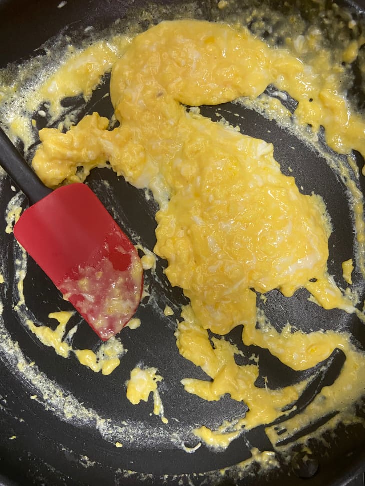 Scrambled eggs in skillet with spatula beside.