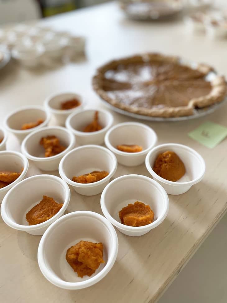 pumpkin pies that have small slivers cut out along with small paper cups filled with different pumpkin fillings for tasting
