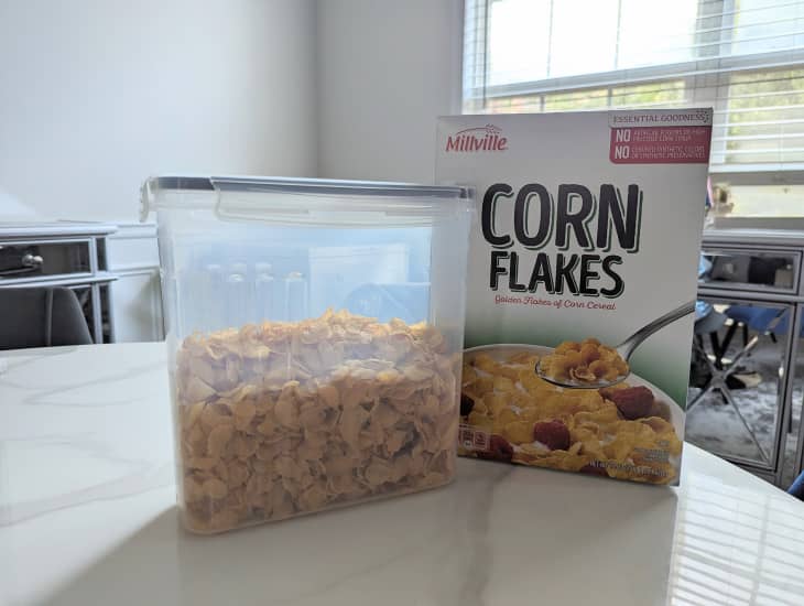 Corn Flakes stored in plastic container on dining room table.