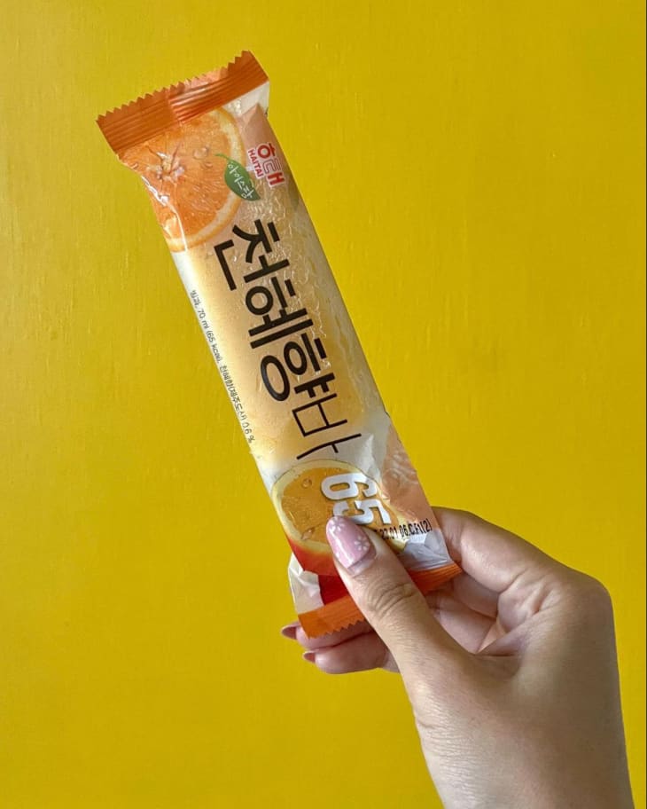 someone holding a Haitai Cheonhyehyang Ice Bar pop in wrapper