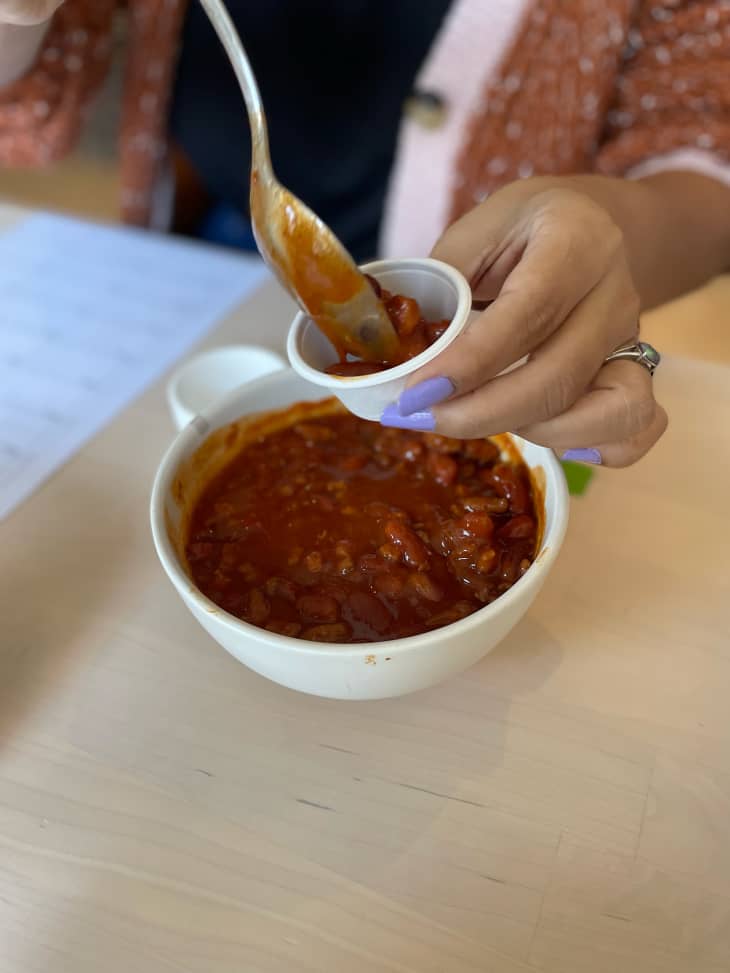 Taste tester putting chili in a tasting cup.