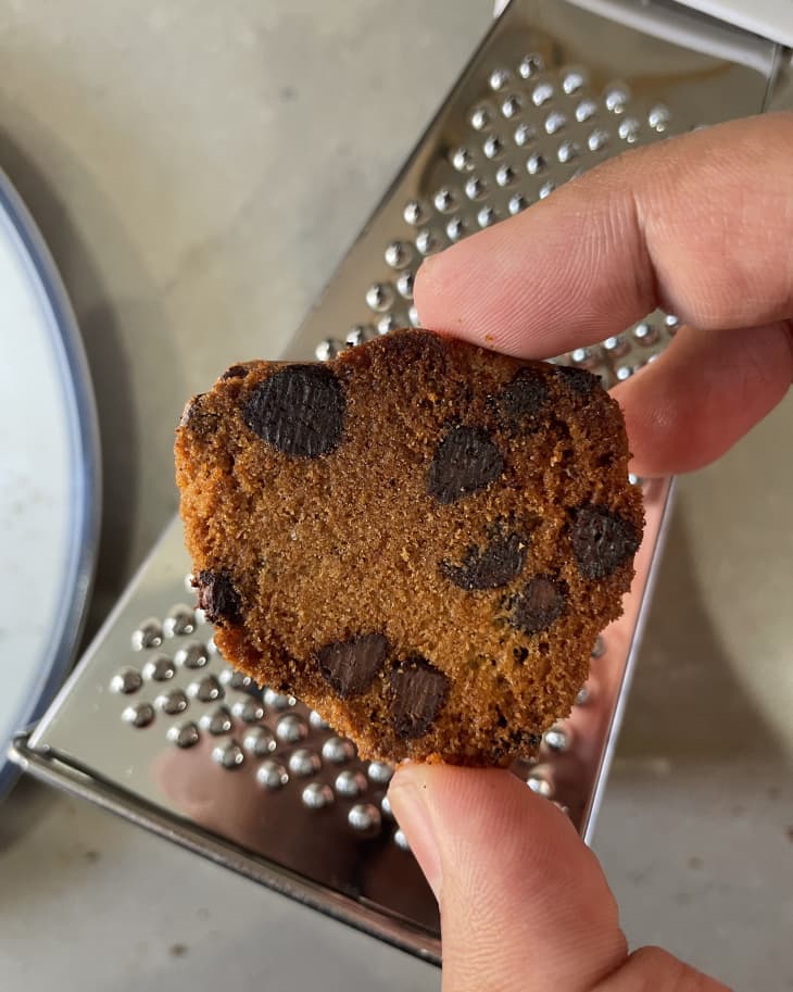 someone holding up a cookie that's had the burnt bottom part grated off with a cheese grater