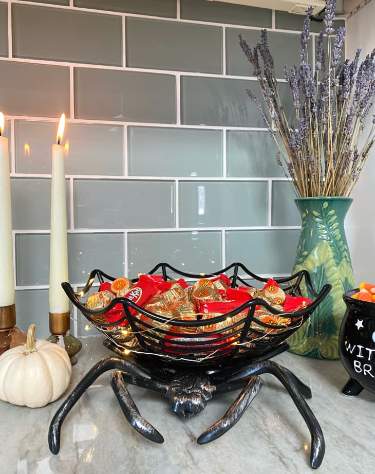 Halloween decor spider web bowl filled with candy on kitchen counter.