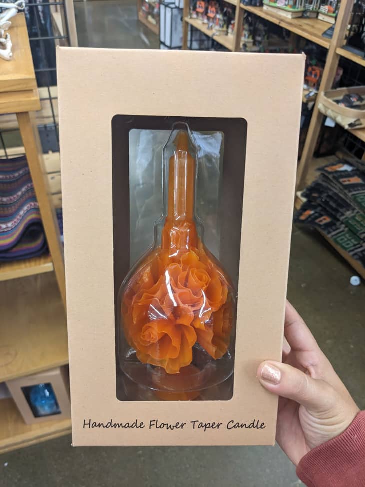 Someone holding flower taper candle in store.