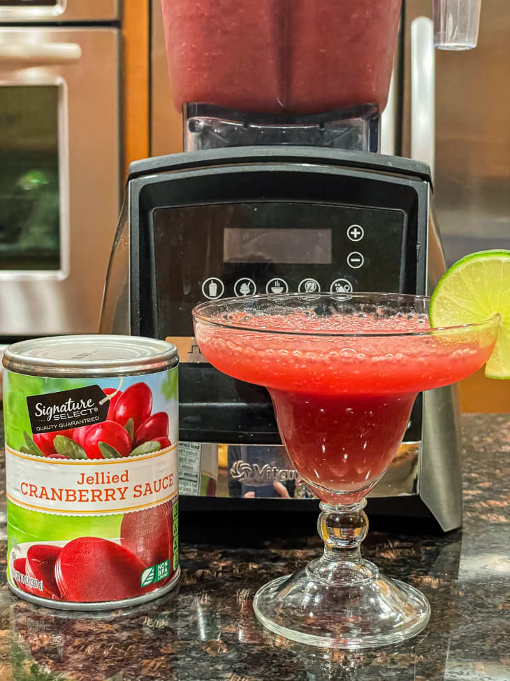 Can of jellied cranberry sauce next to cranberry margarita.