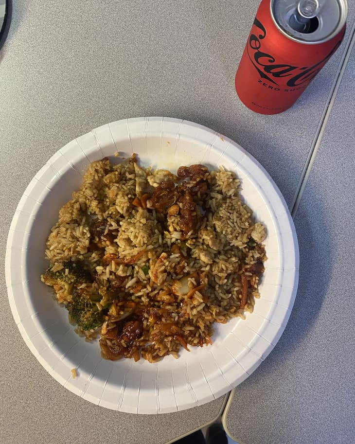 Orange chicken fried rice on plat with can of coke zero