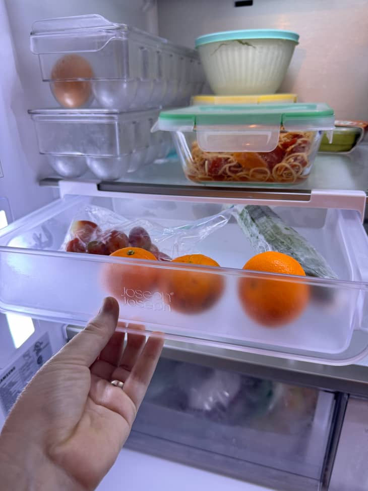 Someone pulling fruit bin drawer open in fridge.