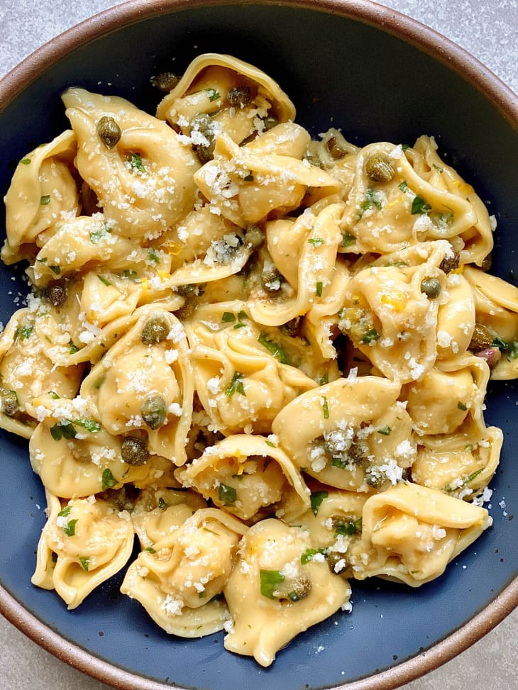 tortellini pasta with capers, parsley, and parmesan on blue plate