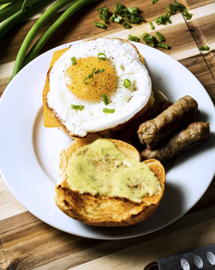 open egg sandwich with round fried egg, toast, and sausage