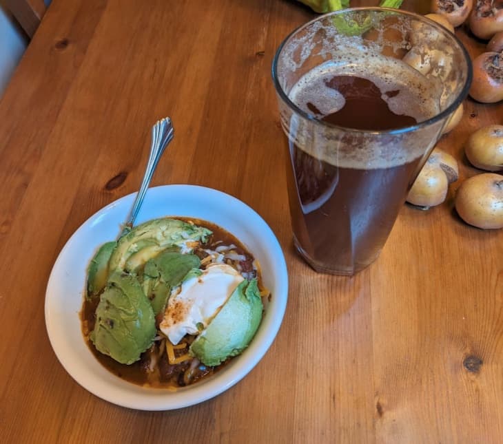 bowl of chili with avocado, sour cream and glass of iced tea