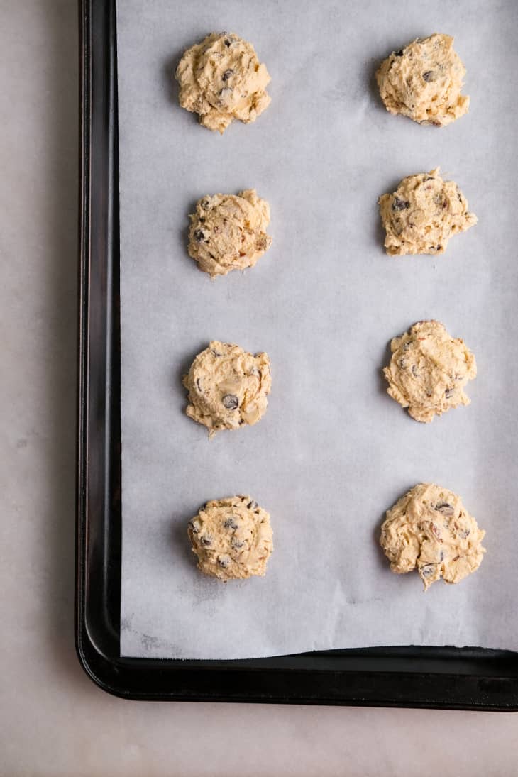 8 balls of raw cookie dough on cookie sheet with parchment paper